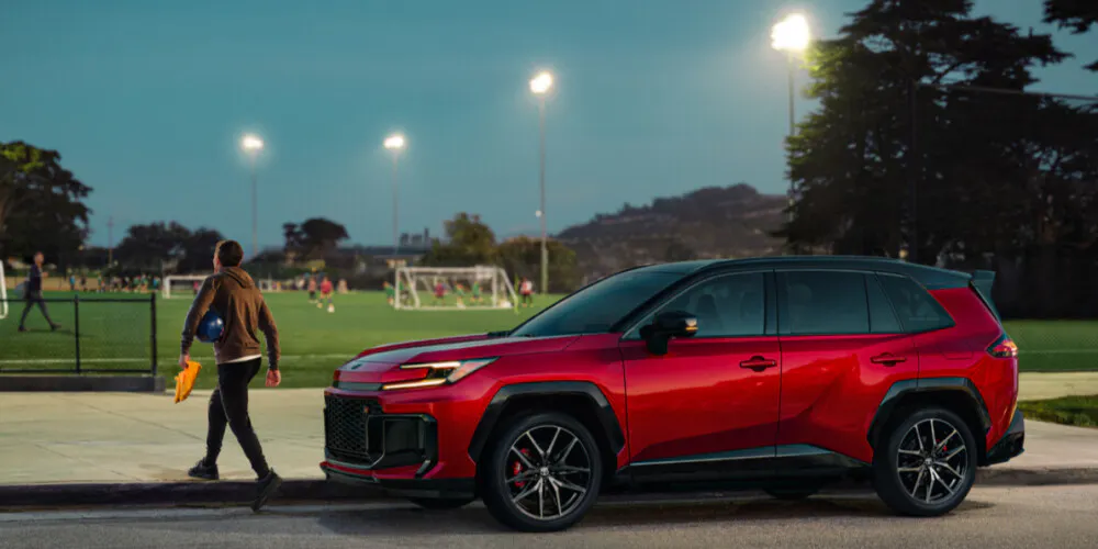 A red RAV4 parked near a soccer field in the evening