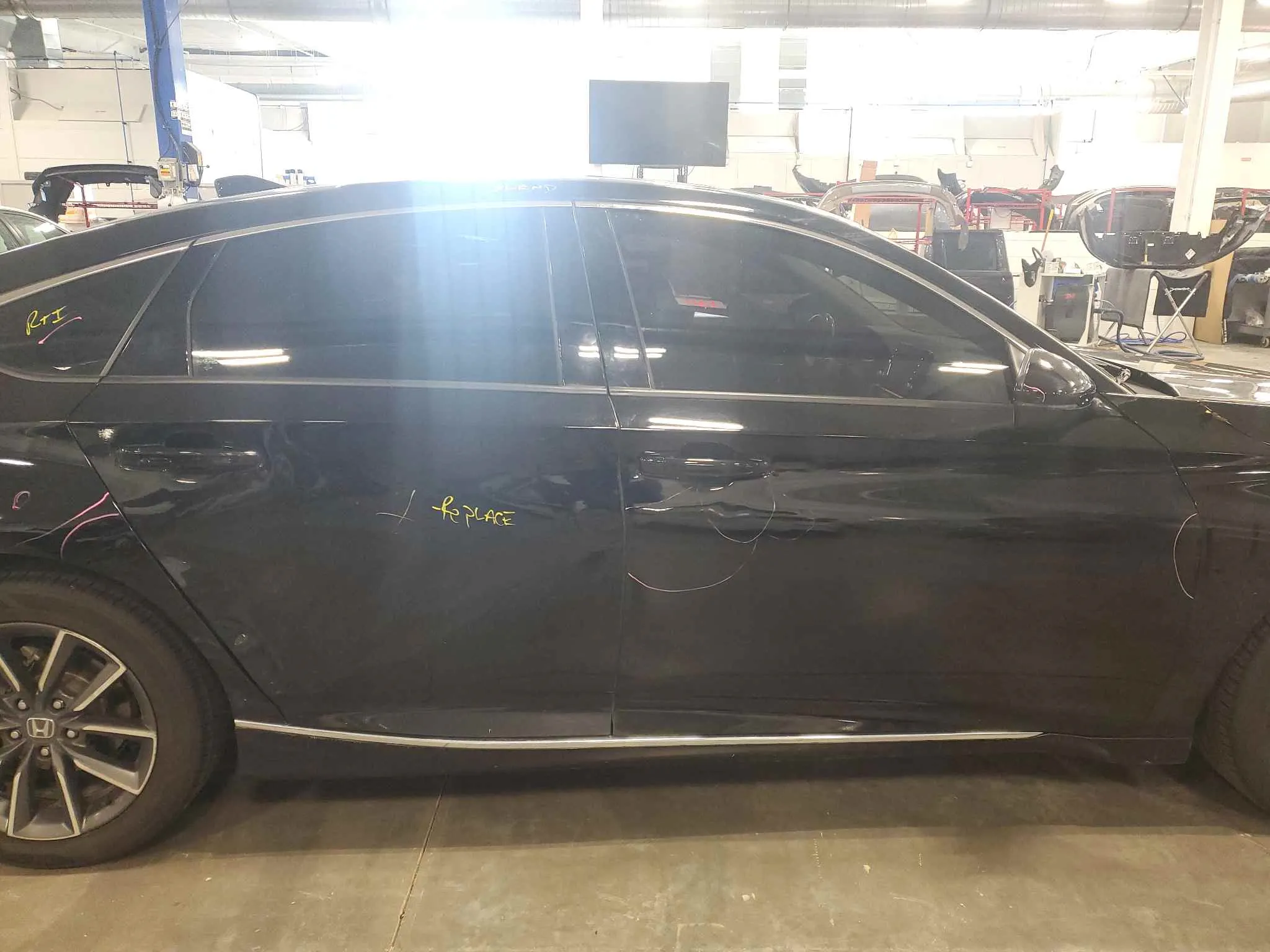 Black sedan with door damage before collision repair