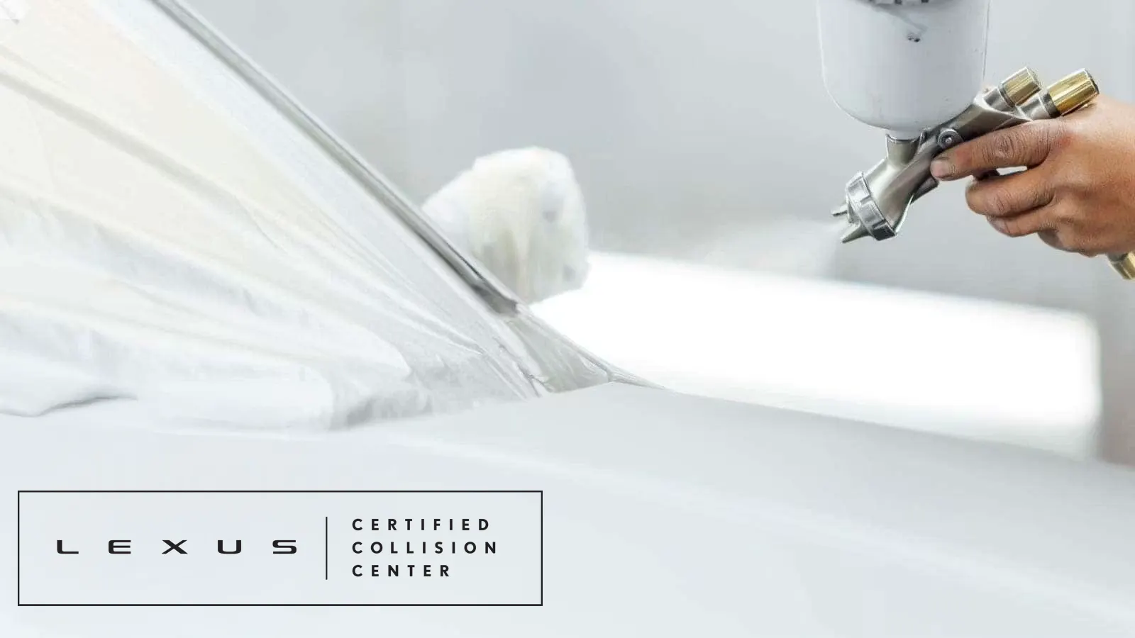 Technician applying precision paint with a spray gun during Lexus Certified Collision Center vehicle refinishing and repair process.