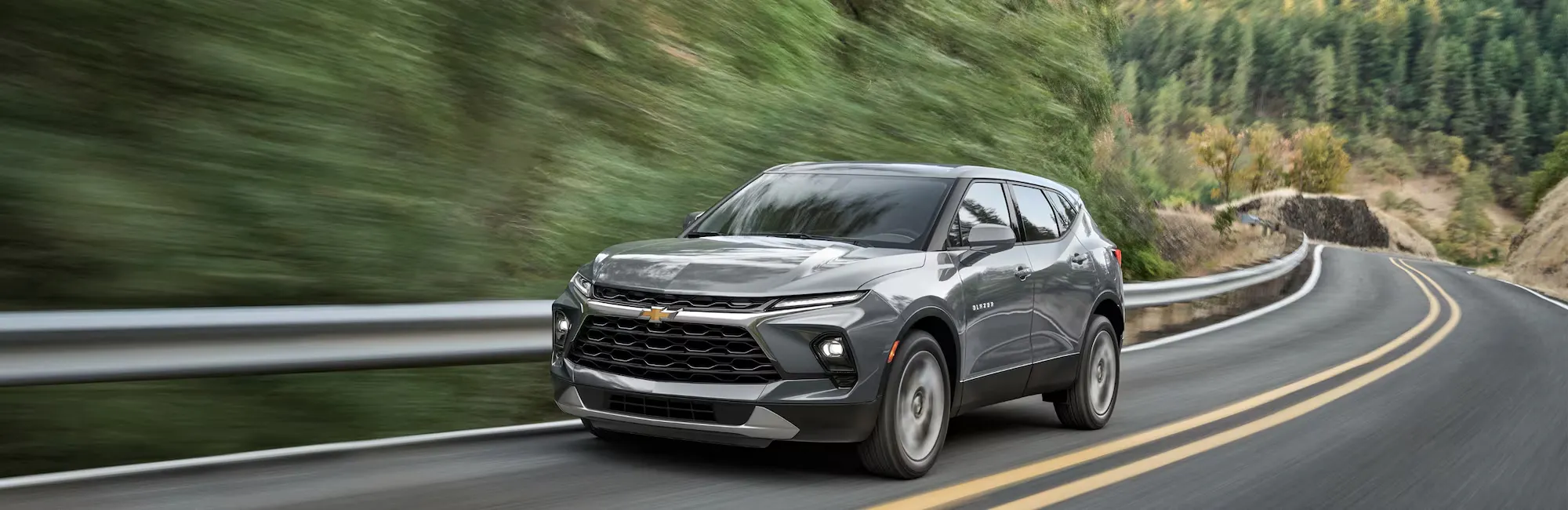 A gray Chevrolet SUV drive on mountain road with blurred background