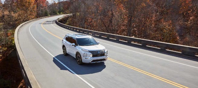 white mitsubishi suv driving down road