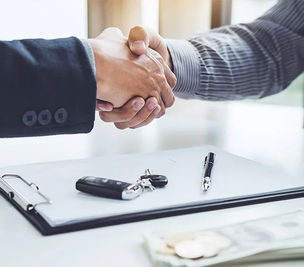 Businessmen shaking hands over car keys and money