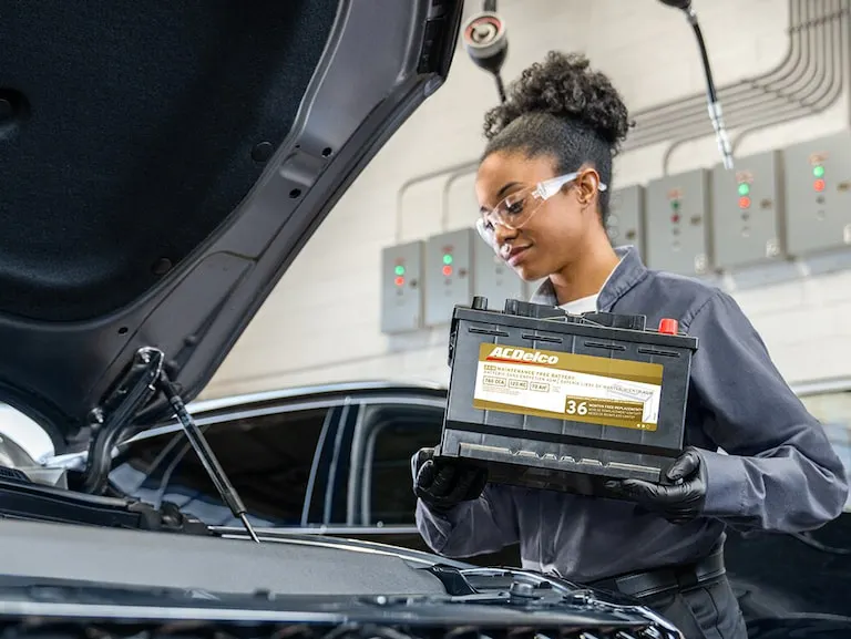 Female service technician prepares to install an AC Delco battery