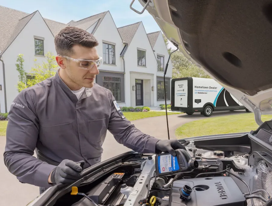 Service technician pouring oil during vehicle maintenance