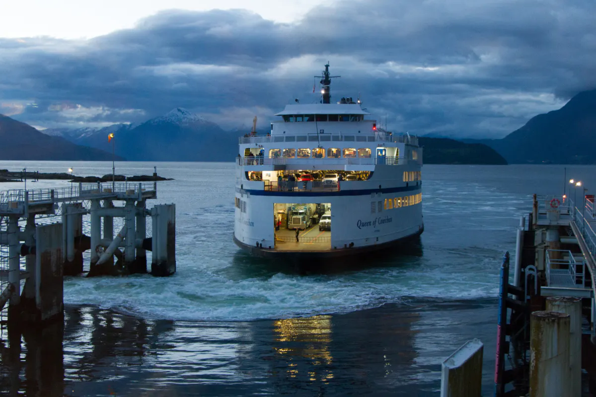 Vehicle ferry docking at a coastal terminal at dusk
