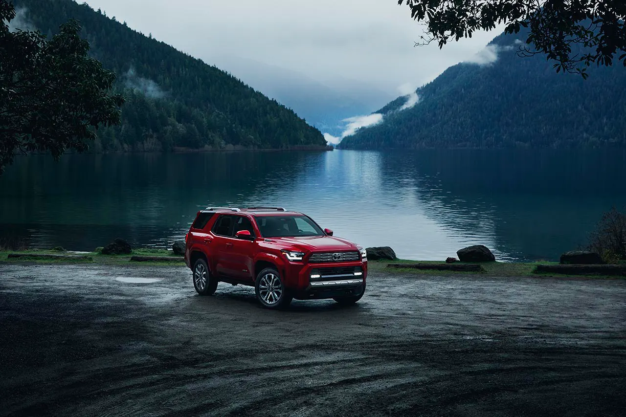 2025 Toyota 4Runner Limited in red parked beside a misty mountain lake surrounded by forested peaks