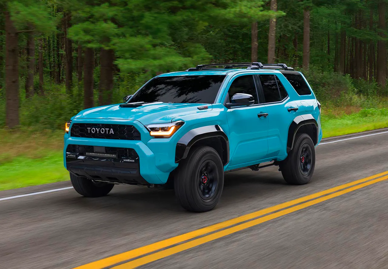 2026 Toyota 4Runner TRD Pro in light blue driving on a tree-lined forest road