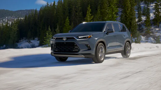 Gray Toyota Grand Highlander driving on a snowy forest road