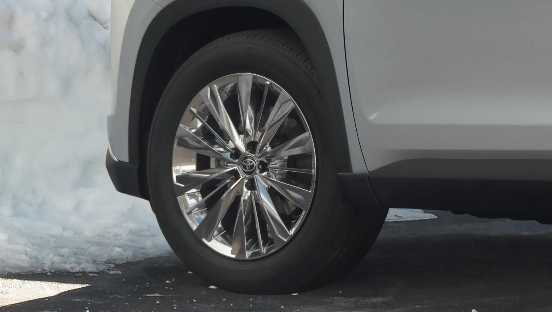 Close-up of a Toyota Grand Highlander alloy wheel on snowy pavement