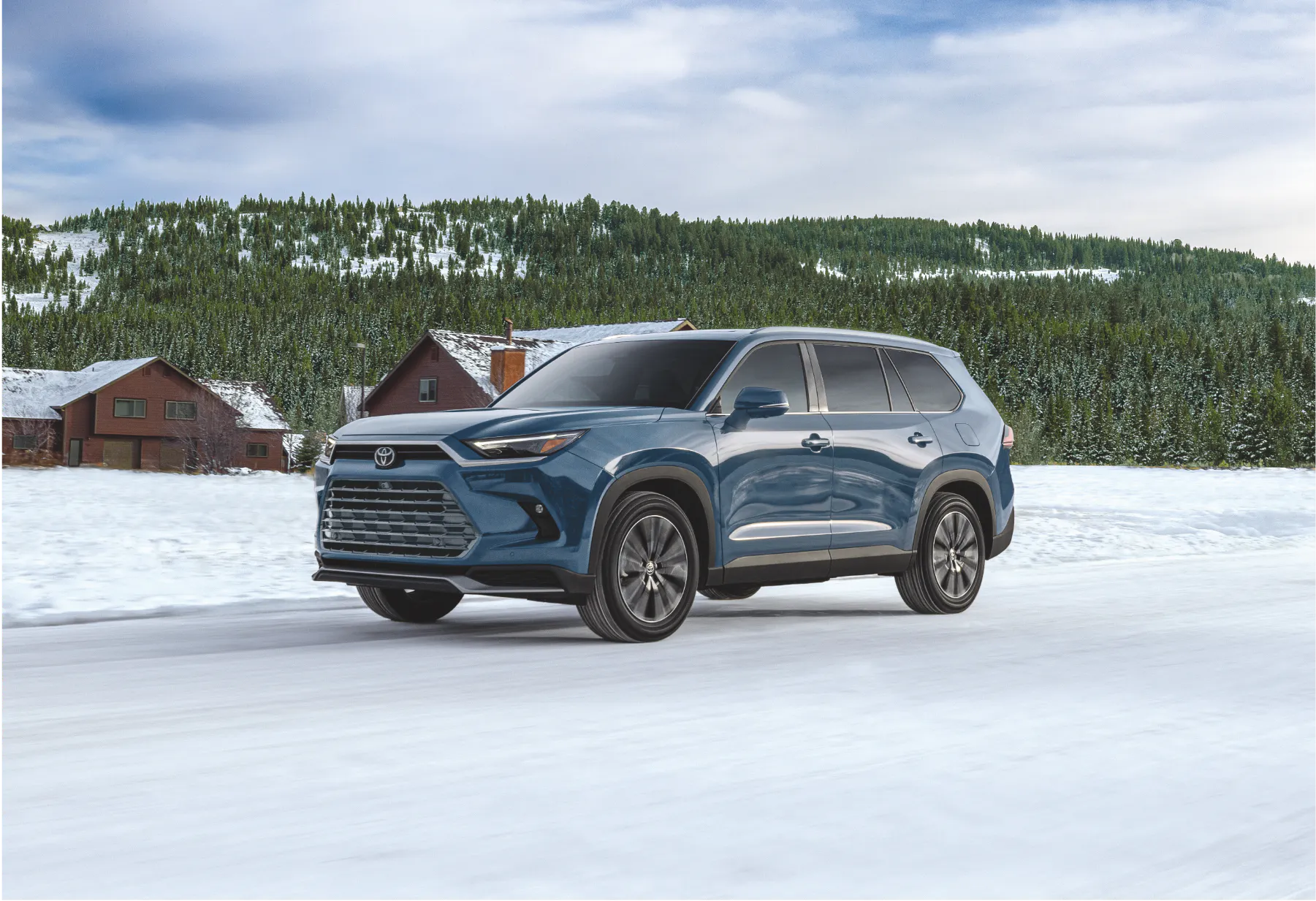 Blue Toyota Grand Highlander parked on a snowy road in front of a mountain lodge