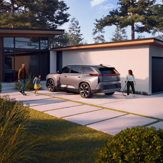 Family arriving home to a silver Toyota Highlander charging in the driveway
