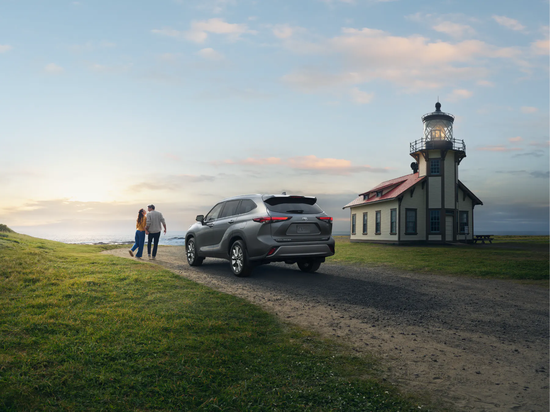 Couple walking toward a lighthouse with a silver Toyota Highlander parked nearby