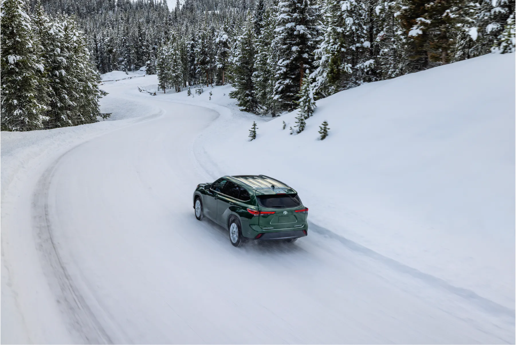 Aerial view of a green Toyota Highlander driving through a snowy Alaska forest