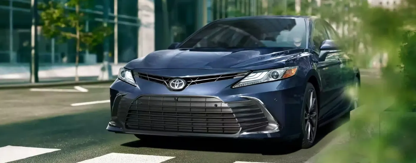 Blue 2023 Toyota Camry driving through a city
