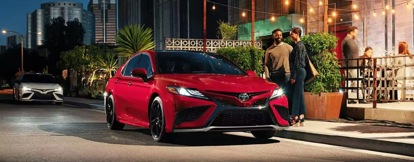 Red 2023 Toyota Camry parked under string lights