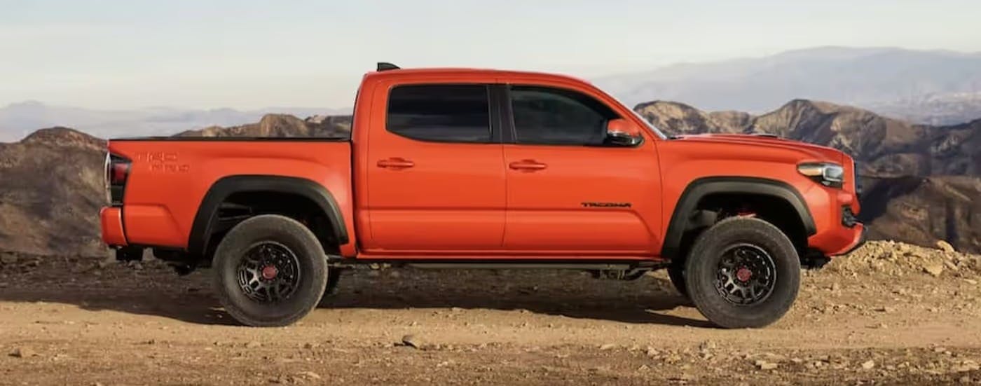 An orange 2023 Toyota Tacoma TRD Pro is shown parked off-road.
