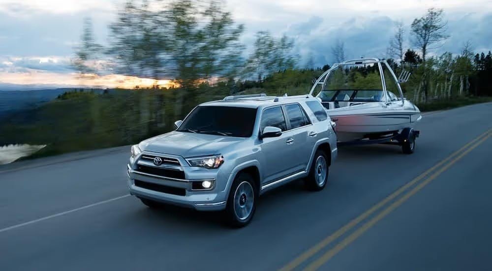 A silver 2024 Toyota 4Runner Limited is shown towing a boat.