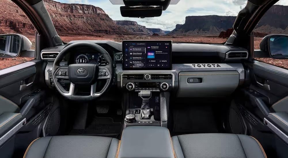 The black and gray interior and dash of a 2024 Toyota Tacoma is shown.