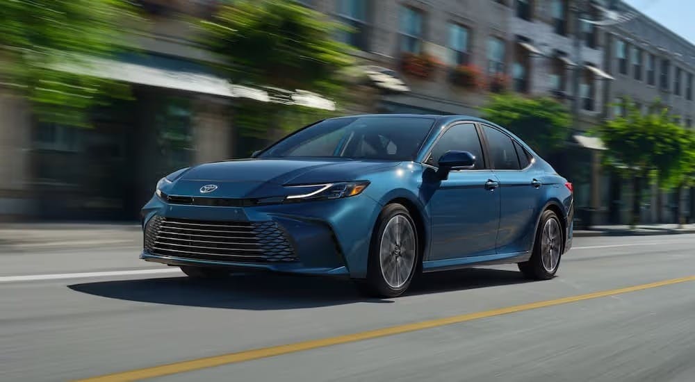 A blue 2025 Toyota Camry XLE driving in a city