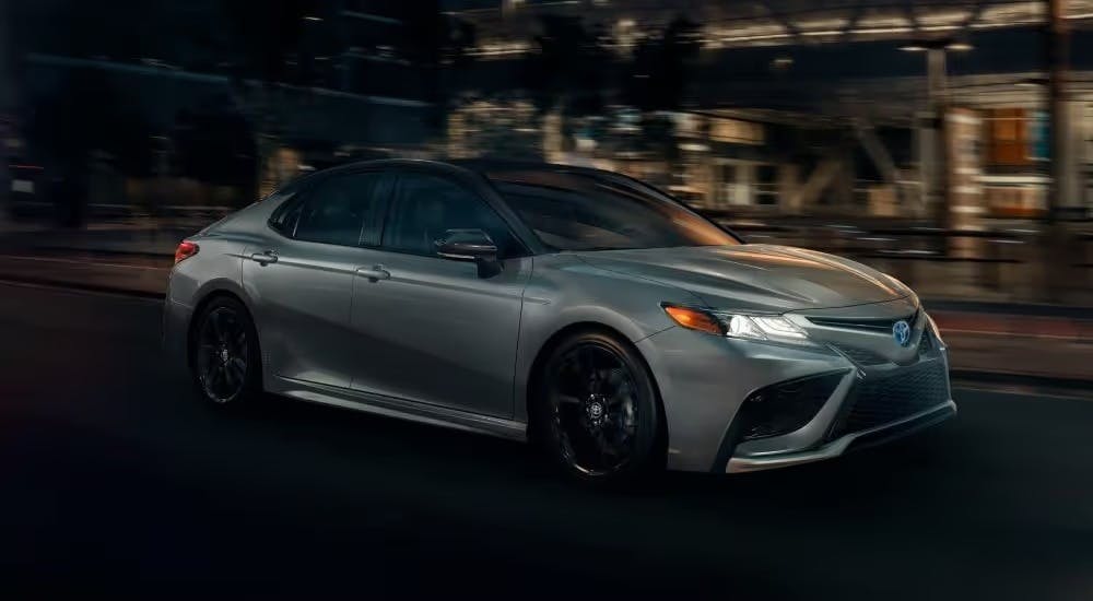 A grey 2024 Toyota Camry XSE Hybrid driving through a city.