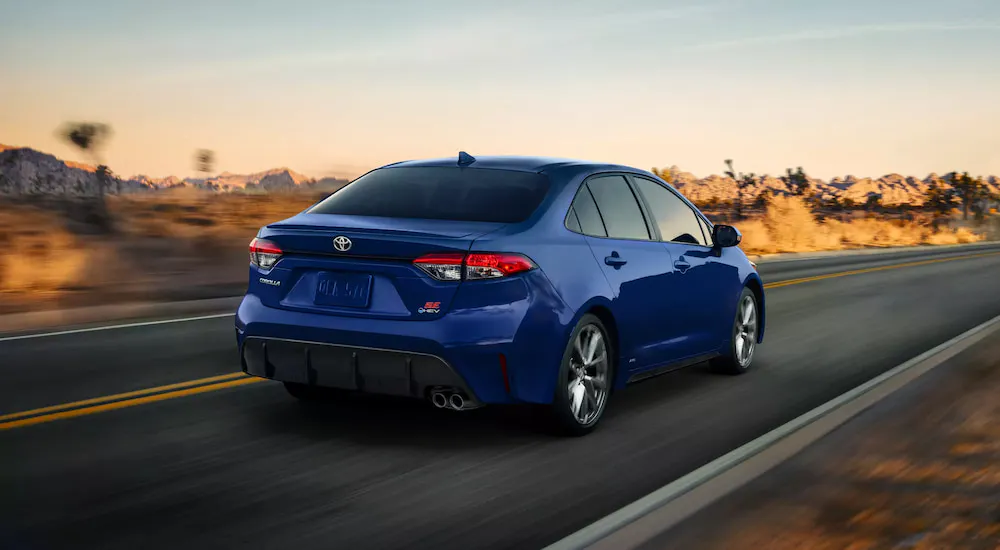 Rear of a blue 2025 Toyota Corolla SE driving down an open road.