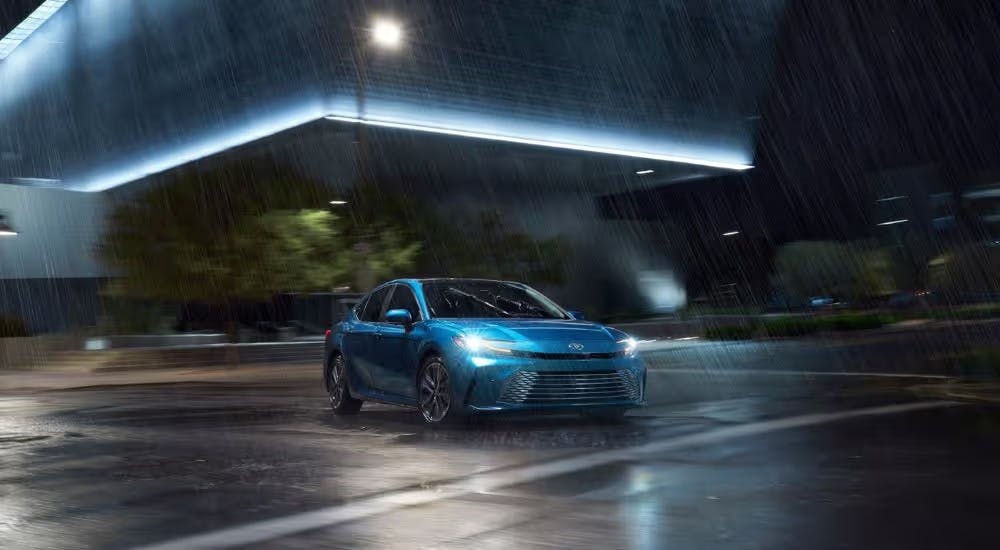 A blue 2026 Toyota Camry XLE parked in the rain at night