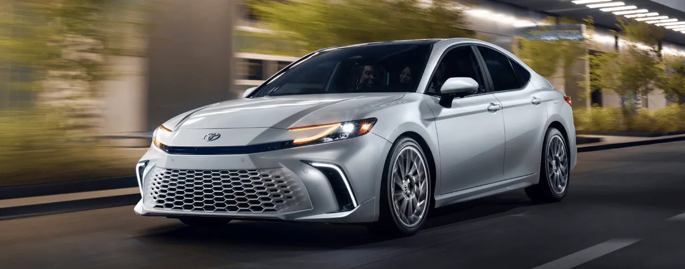 Silver 2026 Toyota Camry driving past greenery