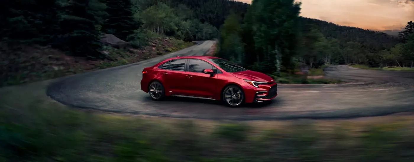 Red 2026 Toyota Corolla driving around a bend.