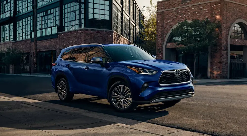 Blue 2026 Toyota Highlander driving down an open road.