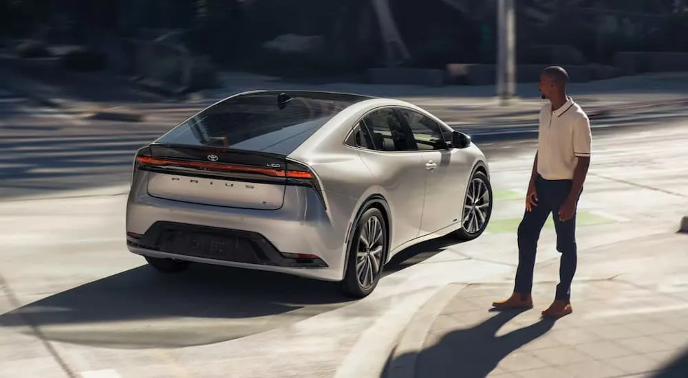 Rear of a silver 2026 Toyota Prius driving down a road.