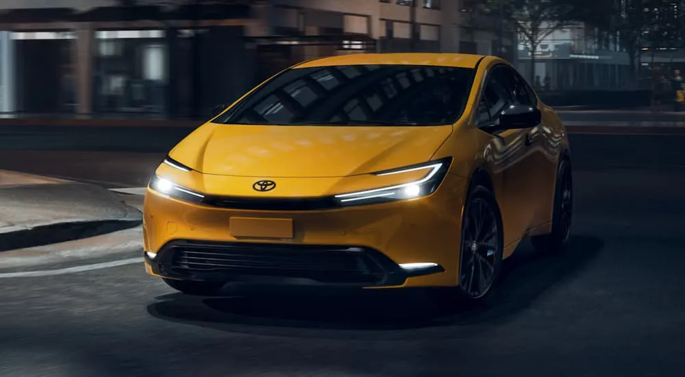 Yellow 2026 Toyota Prius driving around a bend.