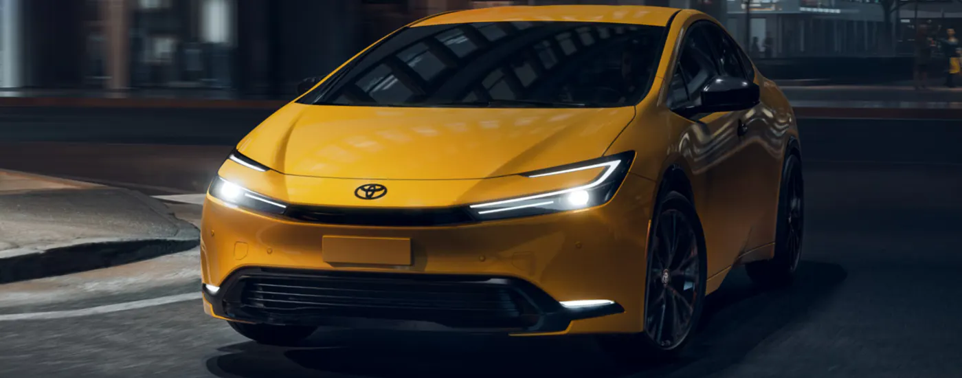 Yellow 2026 Toyota Prius driving around a bend.