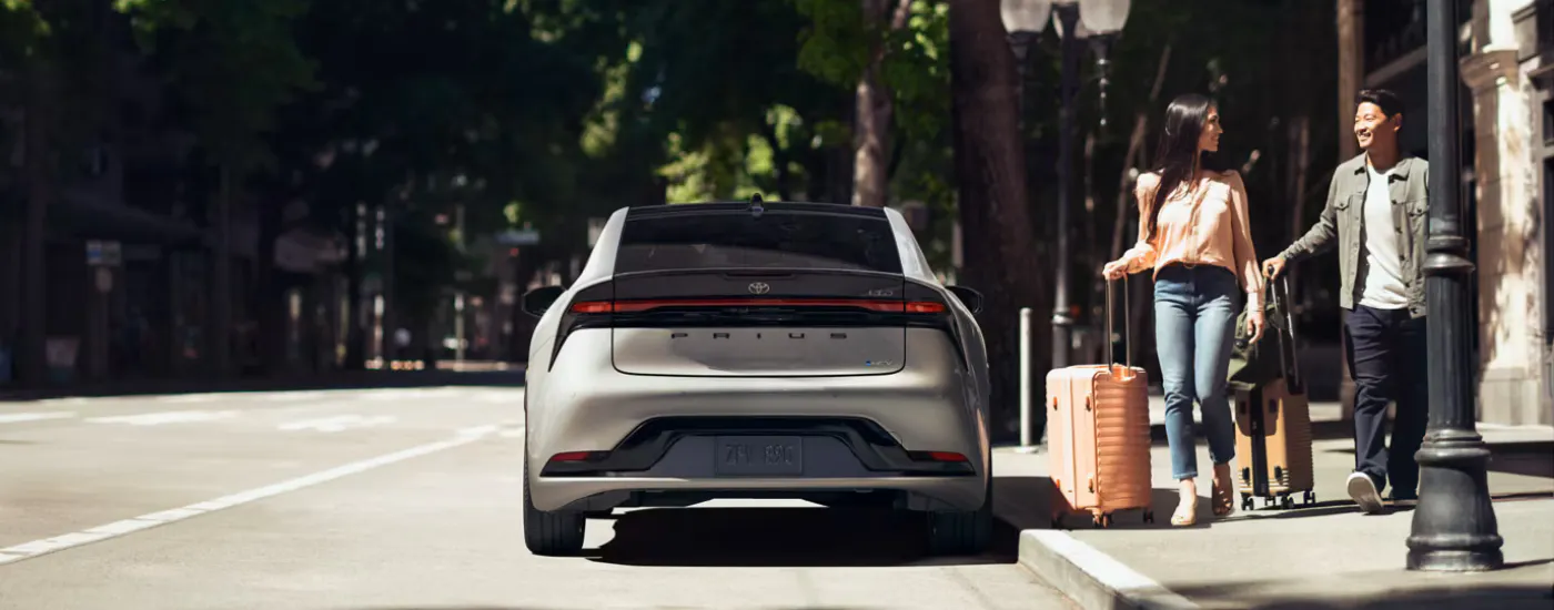 People with suitcases getting into a silver 2026 Toyota Prius