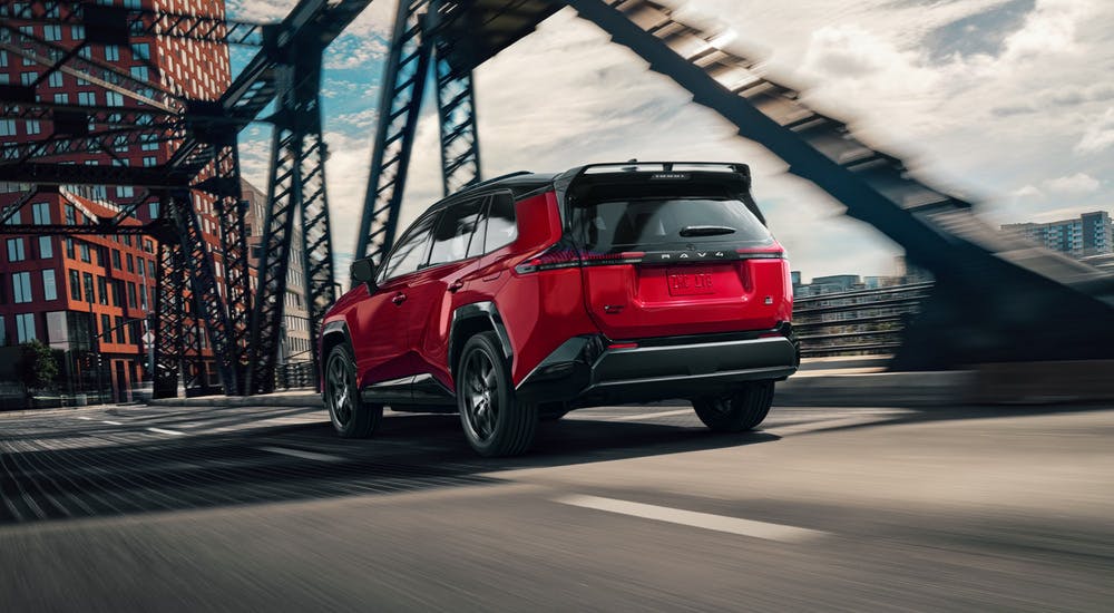 Red 2026 Toyota RAV4 Plug-in Hybrid driving on a city bridge