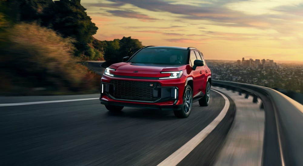 Red 2026 Toyota RAV4 Plug-in Hybrid driving on a winding highway