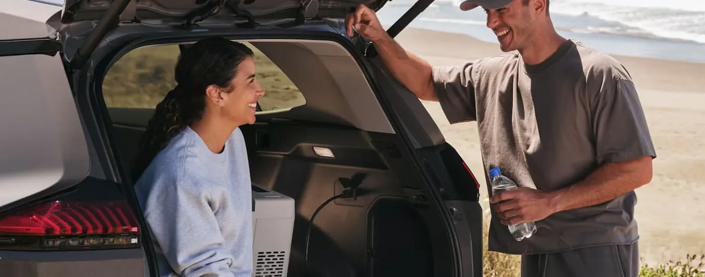 Two people near the rear of a grey 2026 Toyota RAV4