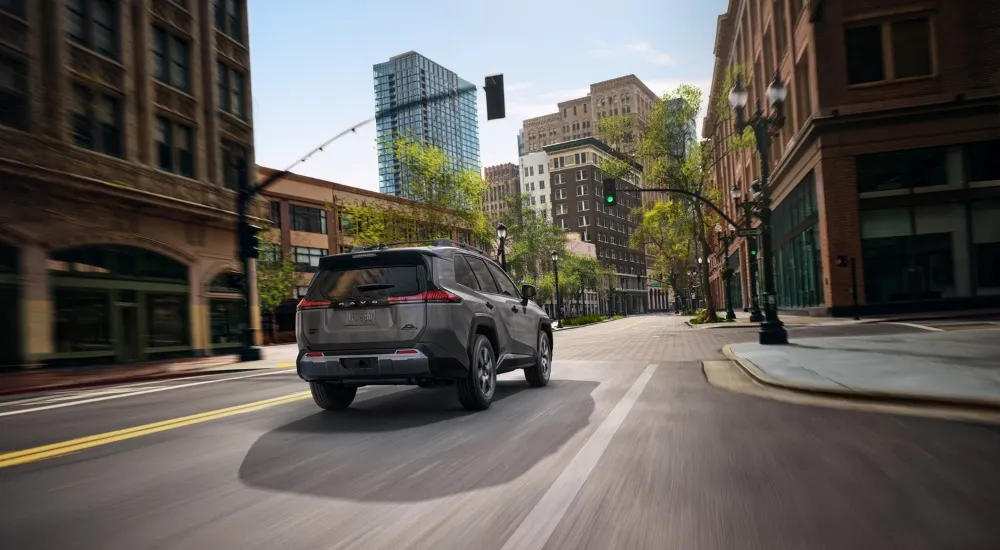 Grey 2026 Toyota RAV4 Woodland driving on a city street