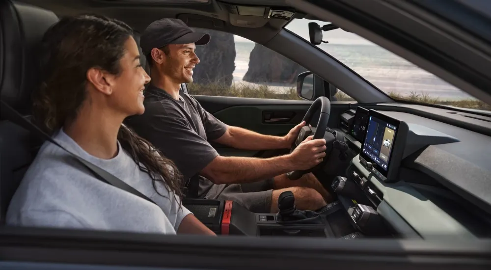 Smiling people driving in a 2026 Toyota RAV4 Woodland 