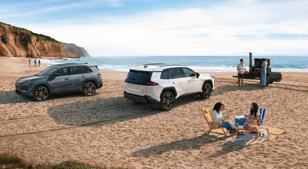 A green and a white 2026 Toyota RAV4 parked side-by-side on the beach