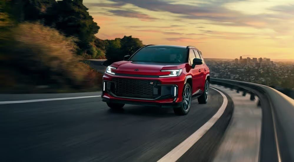 A red 2026 Toyota RAV4 GR Sport driving on a highway.