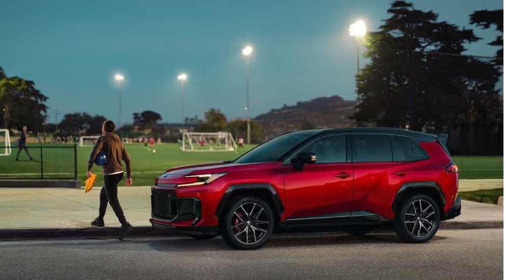 A red 2026 Toyota RAV4 parked near a soccer field.