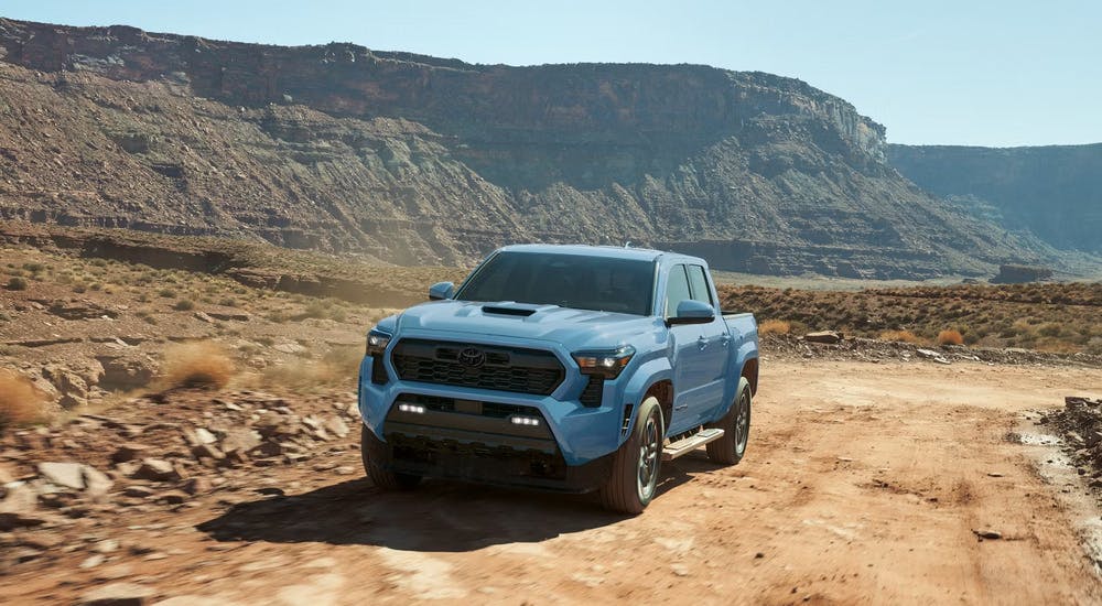 Blue 2026 Toyota Tacoma driving on a dirt road