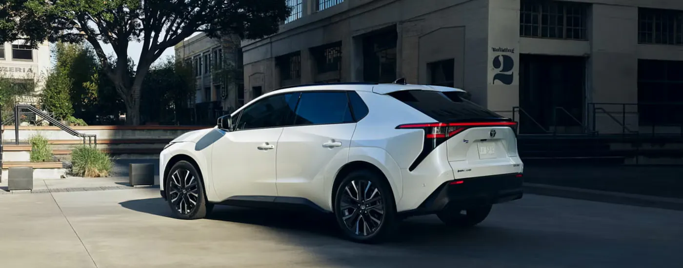 Rear of a white 2026 Toyota bZ parked near a park. 