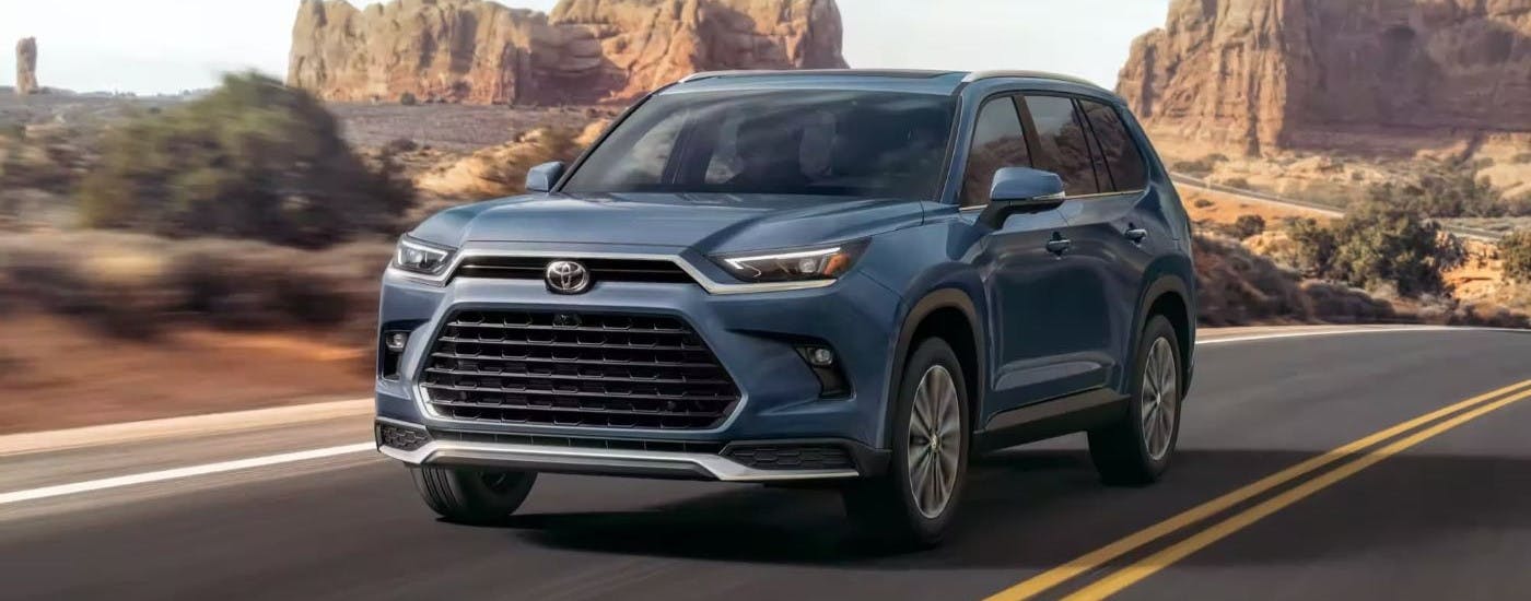 Dark blue 2024 Toyota Grand Highlander Platinum MAX for sale driving down a road.