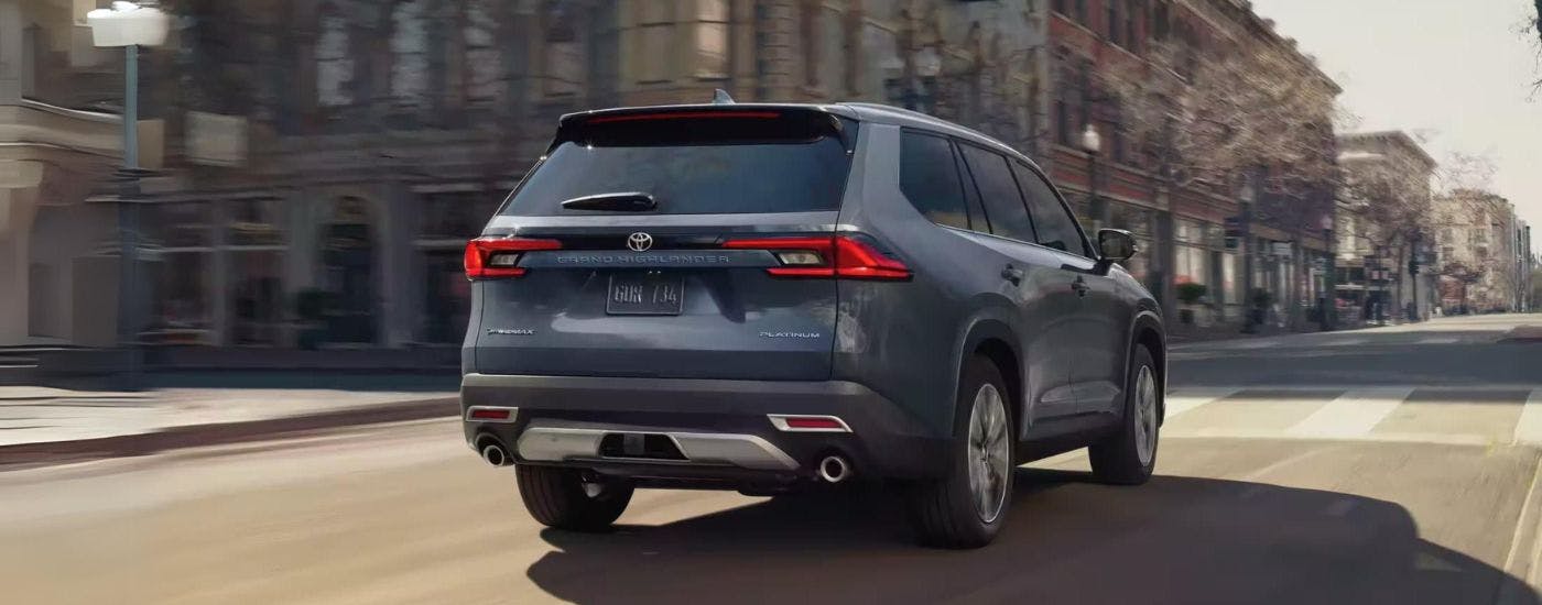 Rear of a grey 2024 Toyota Grand Highlander Platinum driving in a city.