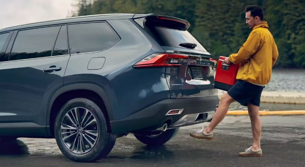 Person loading a cooler into a blue Grand Highlander for sale 