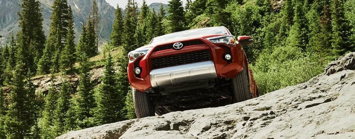 Red 2025 Toyota 4Runner driving off-road up a hill.