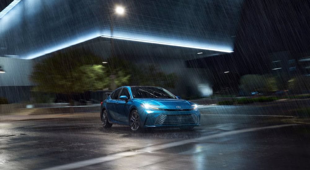 A blue 2025 Toyota Camry XSE driving in the rain at night.