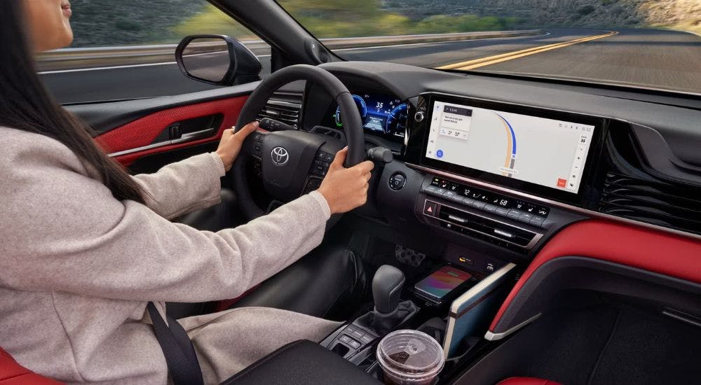A woman driving in the red and black interior of a 2025 Toyota Camry XSE for sale near Kennesaw.