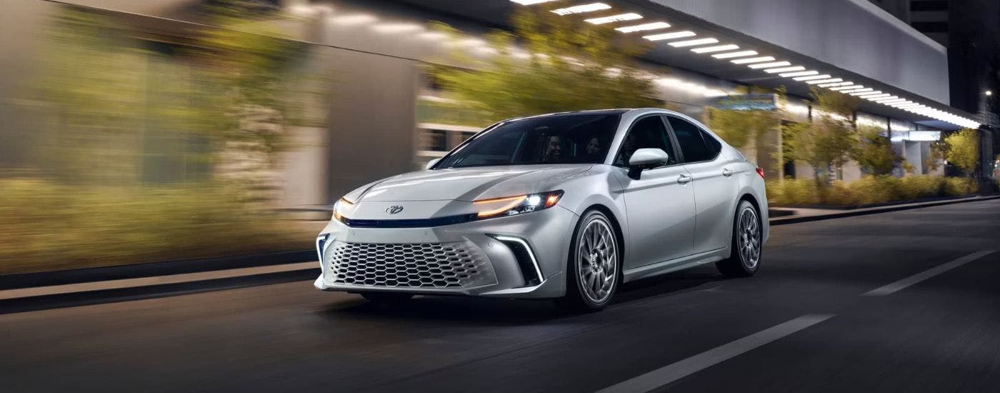 Silver 2025 Toyota Camry XSE for sale near Powder Springs driving down a road.